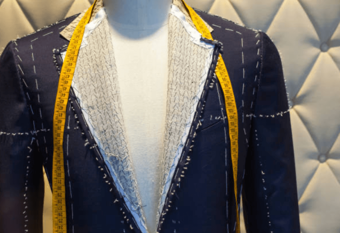 Precision tailoring with measuring tape on premium navy suit fabric, showcasing Federico Ciro's attention to detail and craftsmanship